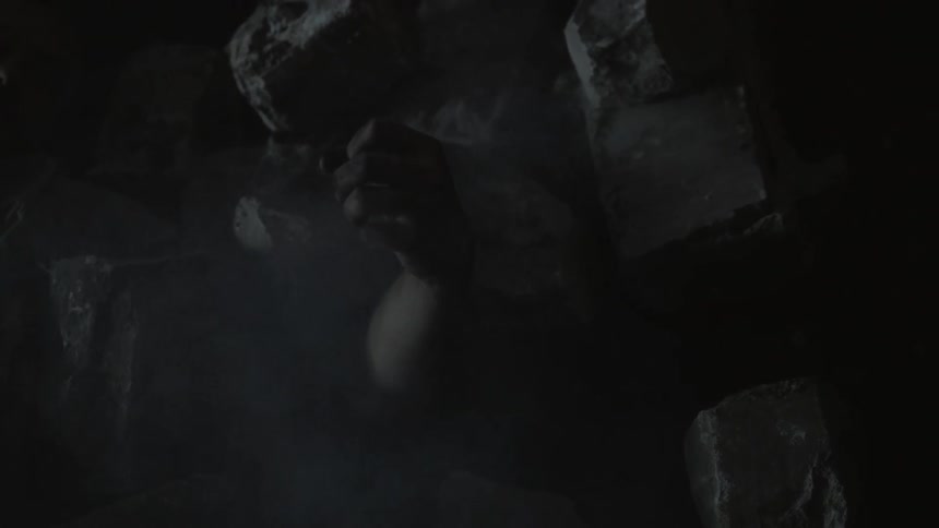 The arm of a person buried under smoky rubble