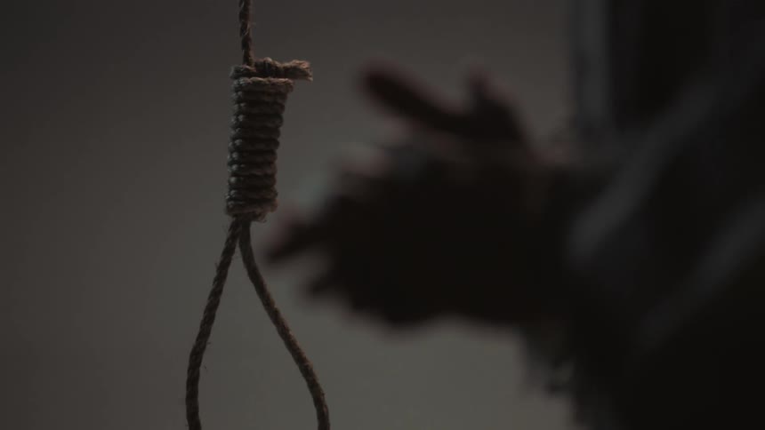 A person is rubbing their hands together in front of a noose