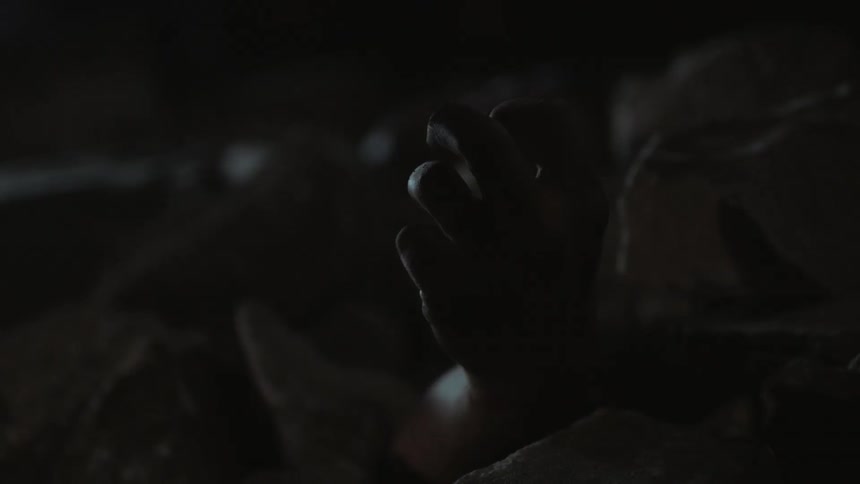 The arm of a person buried under smoky rubble