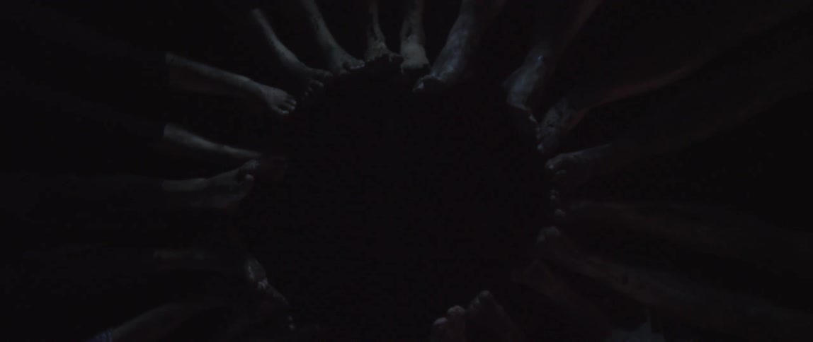 A group of people lay on their backs with their feet forming a circle
