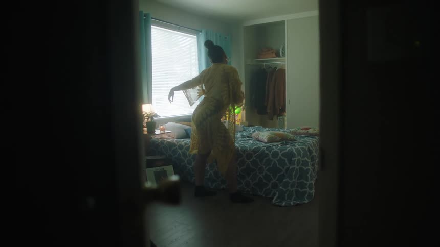 Womandances in bedroom near bed