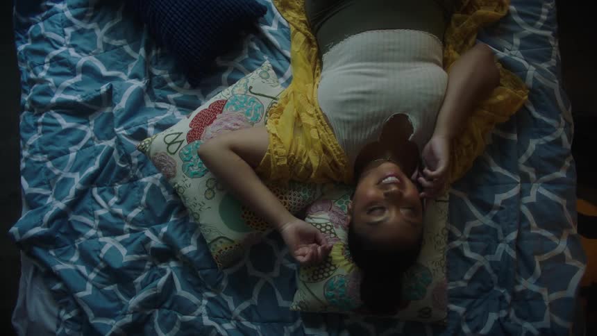 A woman lies in bed while talking on the phone