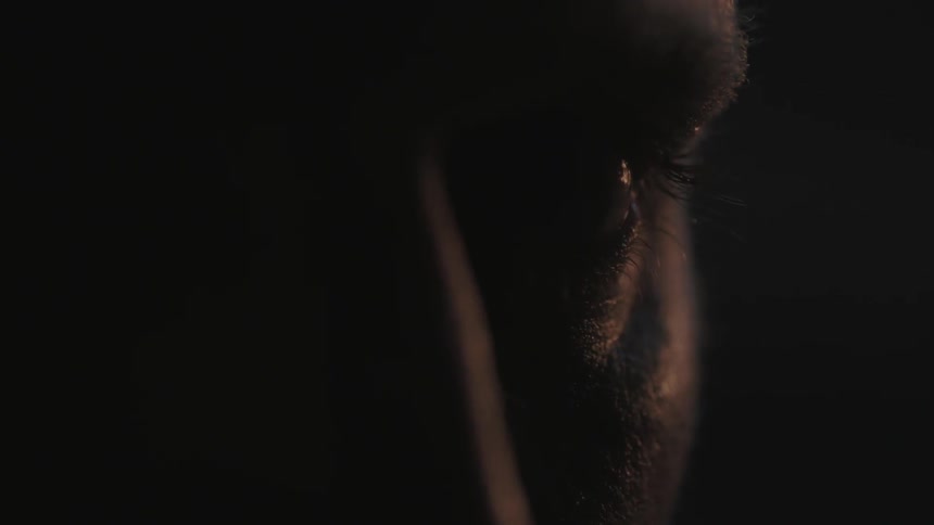 A man in a dark area opens his eyes
