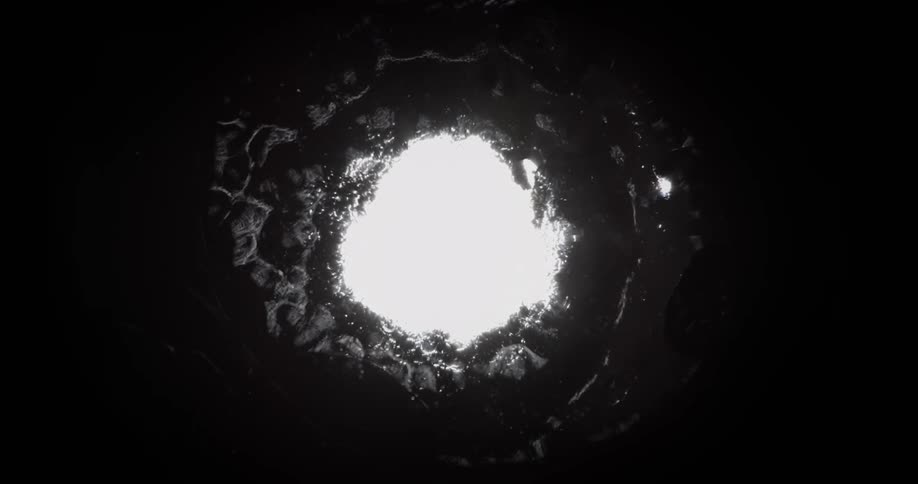 Bright white light shines on the shimmering reflecting surface of a liquid