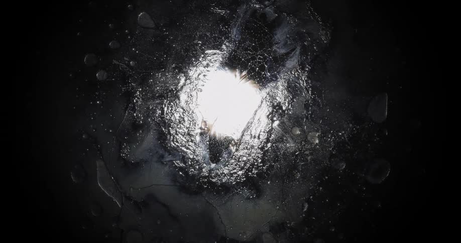 Clear liquid slowly flows above on a transparent surface and distorts the light overhead
