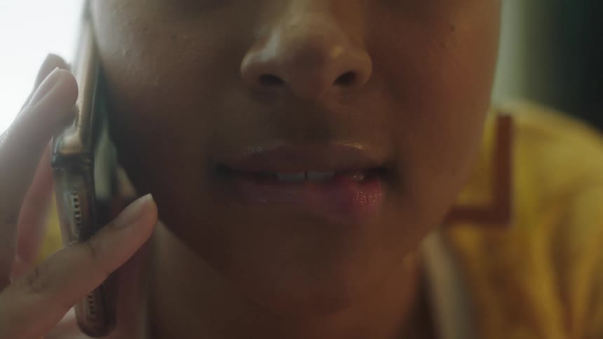 A woman smiling and biting her lip while on a phone conversation
