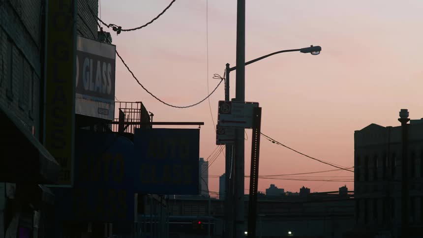 The sun is below the horizon and the silhouettes of buildings and utility poles are seen