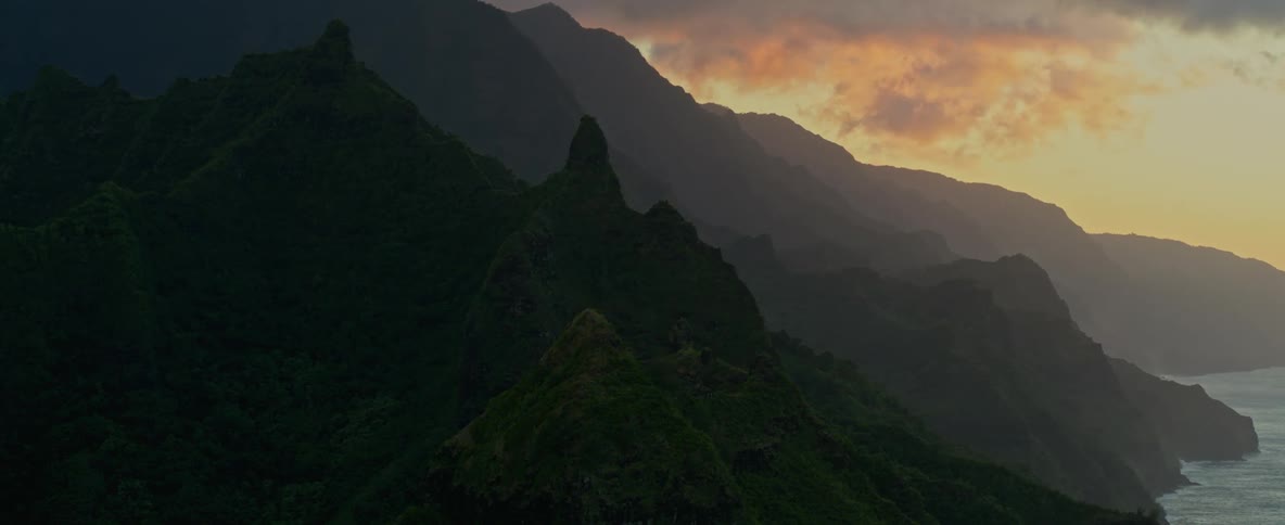 Tall and jagged mountains slope downward until they meet the ocean