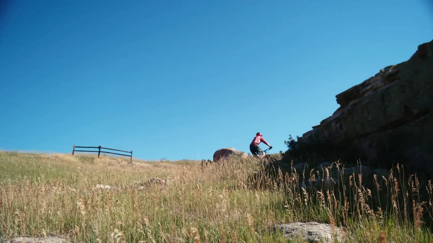 A biker biking up a hill near hilly area