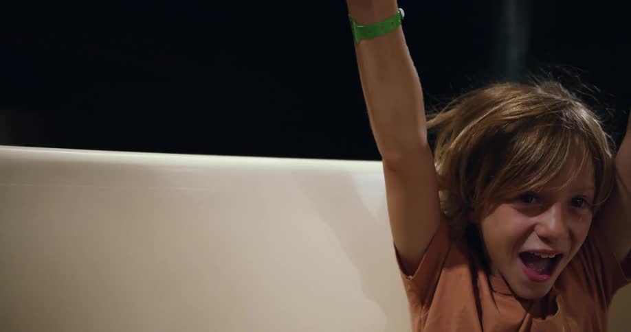 A child waves his arms around while on the amusement park ride