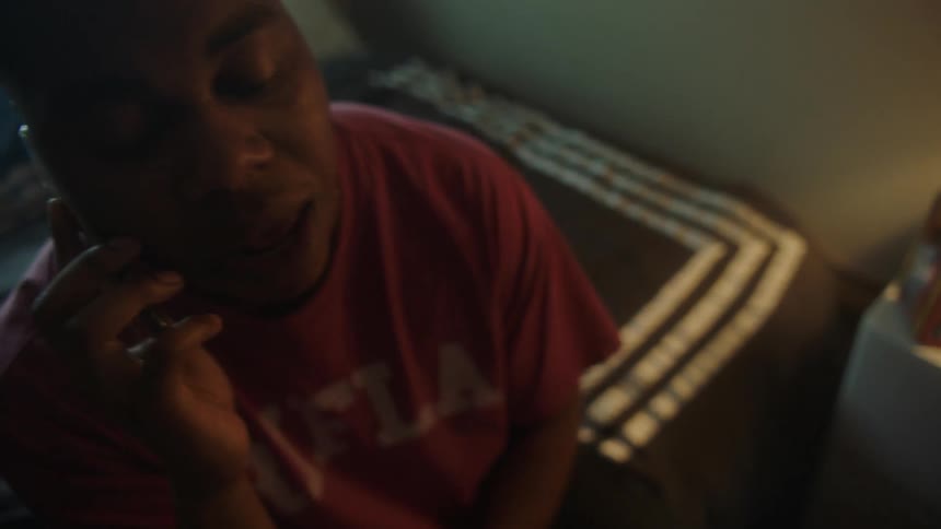 A man is talking on the phone in his bedroom
