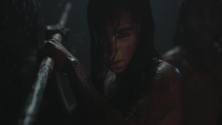 A muddy person holds a spear in the rain