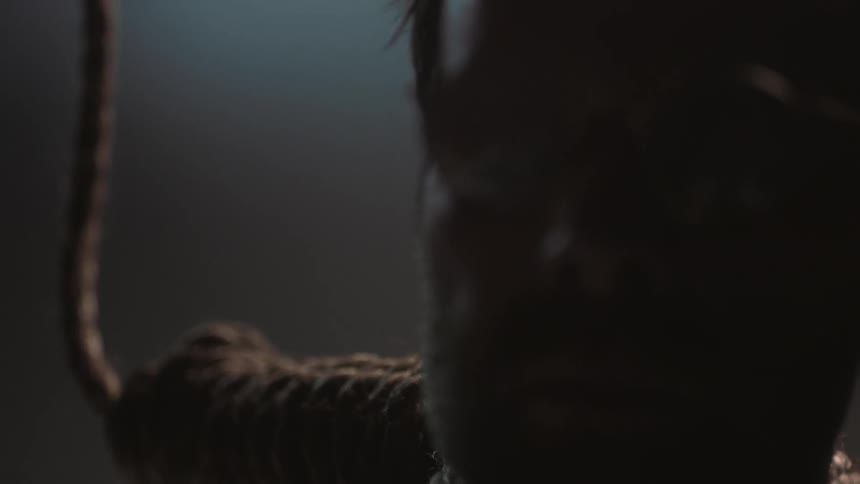 A man in glasses is wearing a noose
