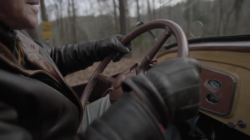 A man wearing goggles and gloves is driving a car