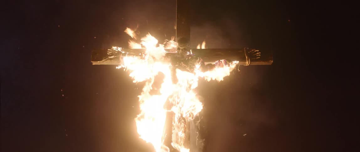 A body on a cross is on fire at night