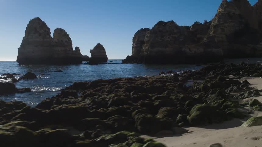 Rocks dot the coastline in the daytime
