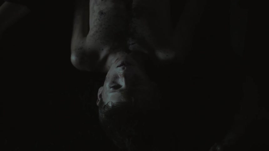 A dirty child lies in a dark room
