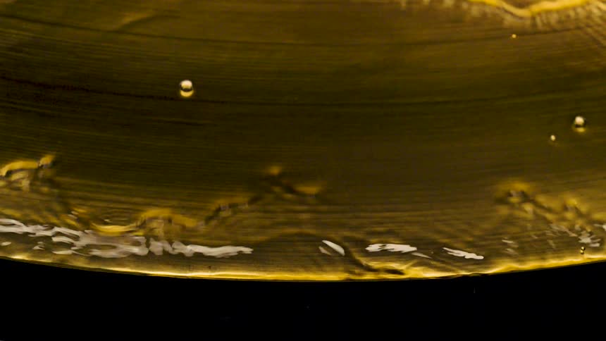Water flows to edge of golden metal plate and drops over the side