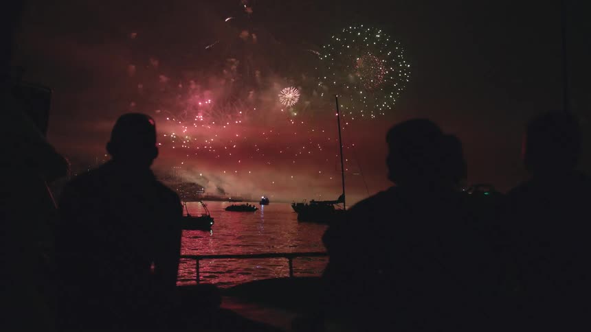 A group of people watching fireworks over water