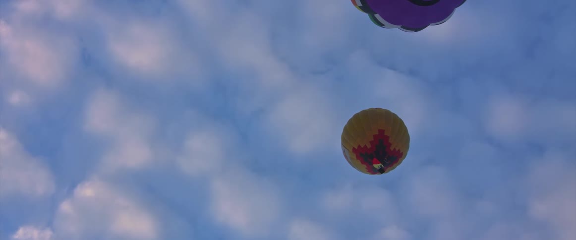 Two hot air balloons float higher in the sky
