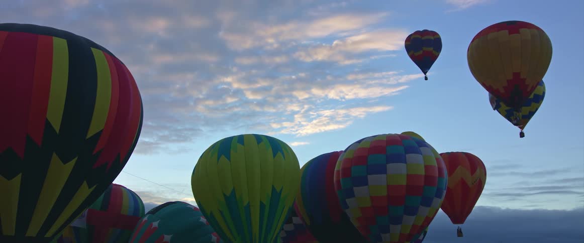 Hot air balloons are floating in the sky among the clouds
