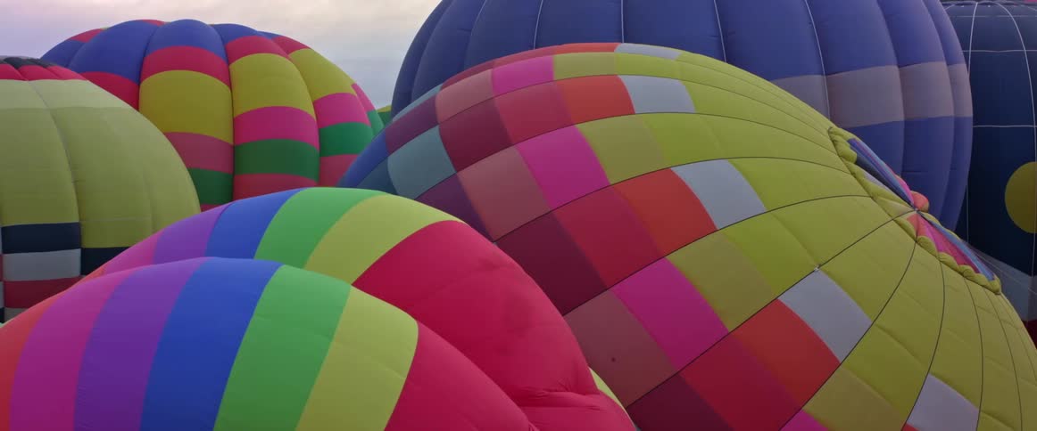 Colorful hot air balloons are moving in the wind as they get ready to take off