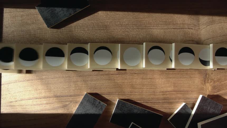 Standing wooden blocks falling like dominoes over a table