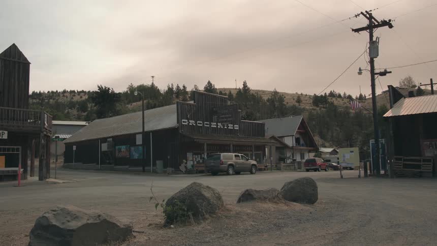 Vehicles parked in front of store in small town on a cloud day