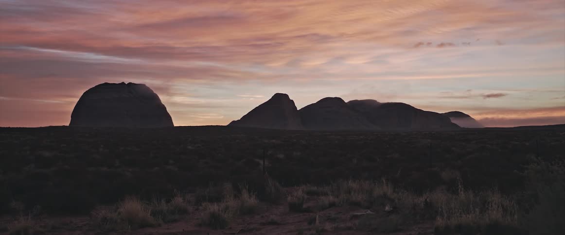 Landscape of dry terrain and distant mountains at dusk