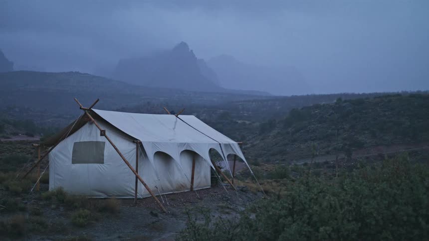 A white tent outside in stormy weather near mountains