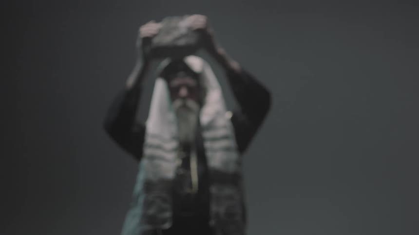 A bearded man lifts a brick over his head