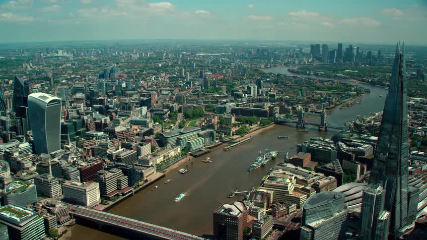 Ships move along river through middle of city