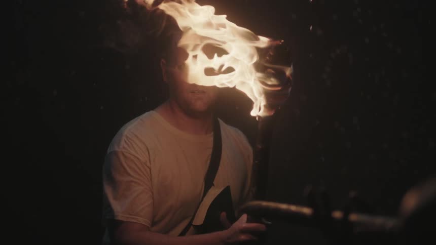 A man walks in a dark area with a torch