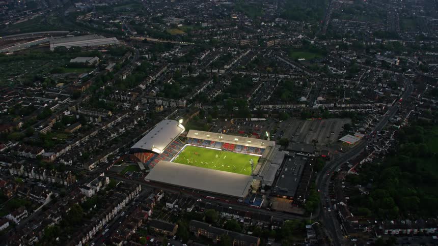 A soccer game takes place in a stadium in the center of a city