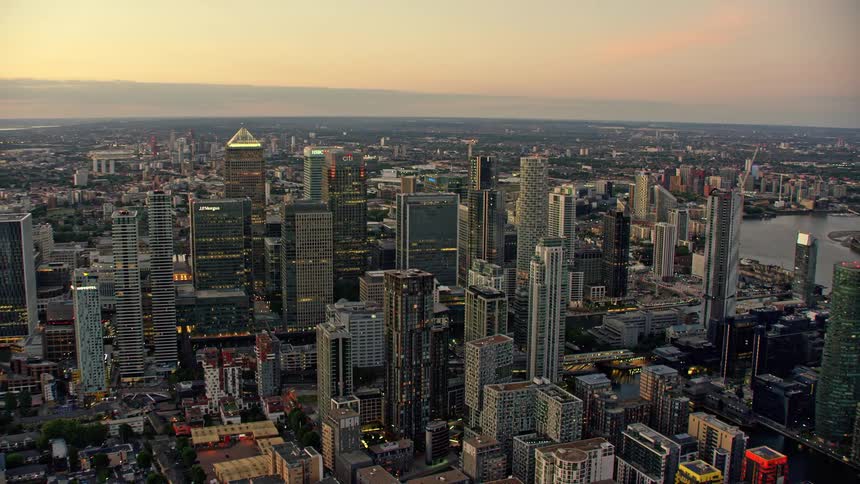 An aerial view of high rise office buildings and construction cranes in a city on the river