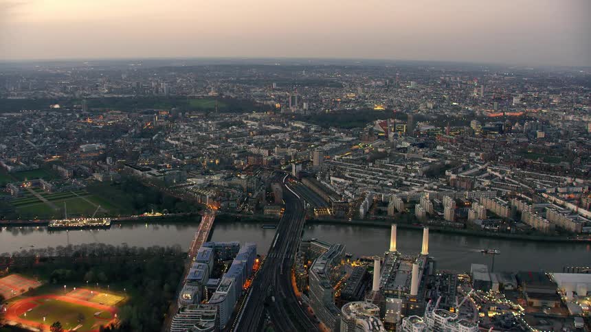 An aerial of a city with a stadium lit up and a bridge crossing the river