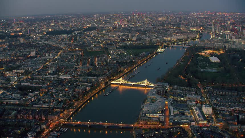 Aerial view of a city following a river with lit bridges