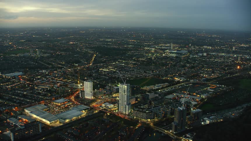 Construction cranes work on building near river in city stretching to a hazy horizon