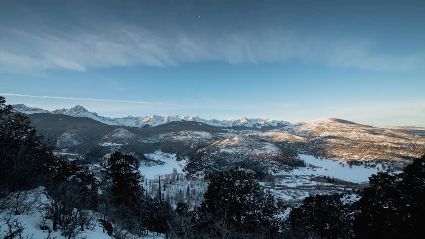 Landscape with snow covered mountains in the distance and trees in the foreground