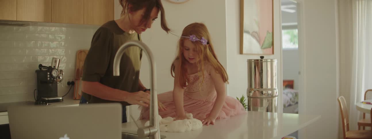 Women and child kneading dough on the kitchen counter