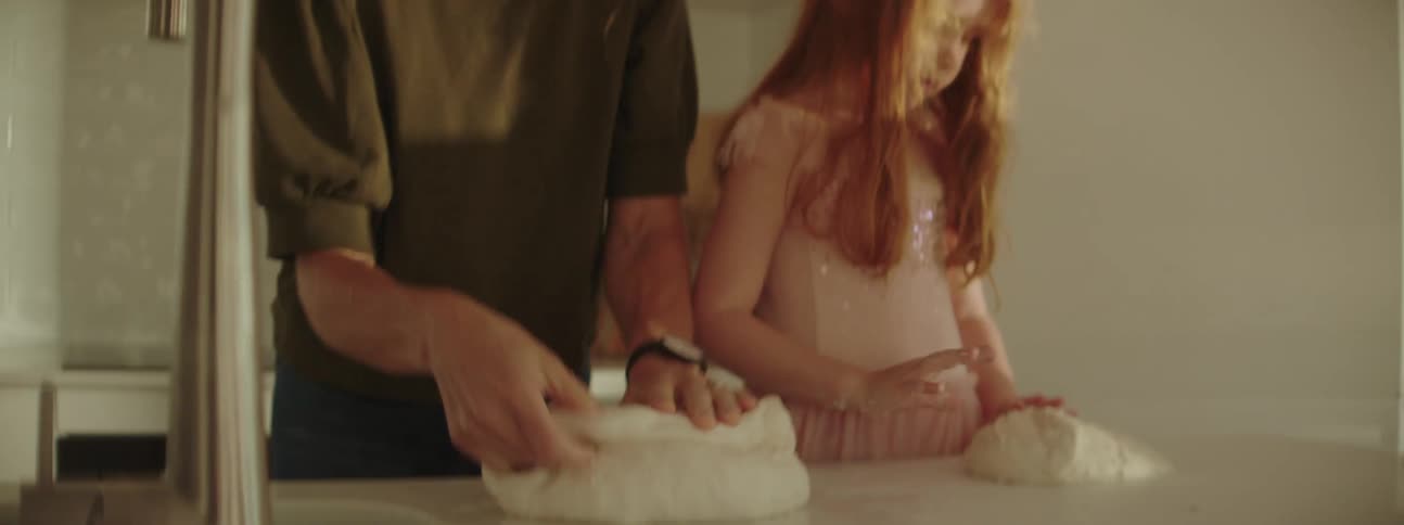 A mother and daughter knead dough as they bake at home