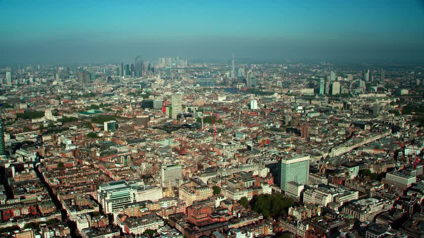 Aerial view of buildings streets and distant skyline near river thames in london