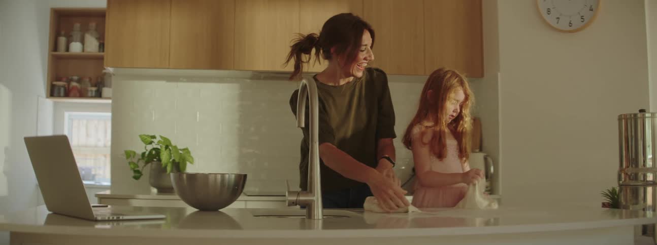 Women and child kneading dough while laughing and smiling at each other