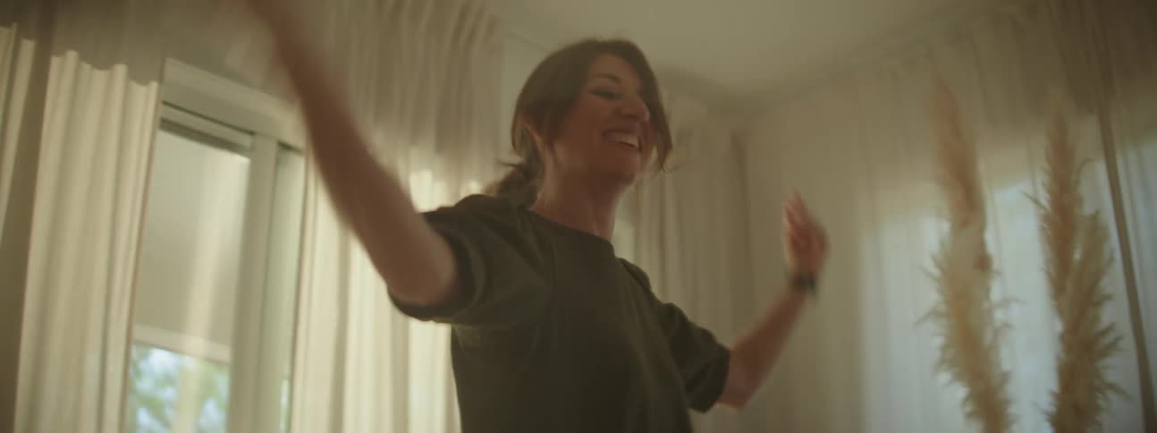 A woman is dancing in the living room with her young daughter