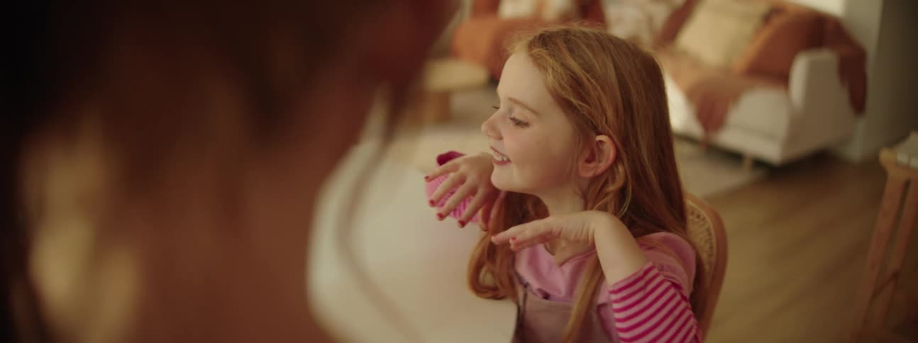 Woman holds up mirror allowing young daughter to examine her makeup and polished nails