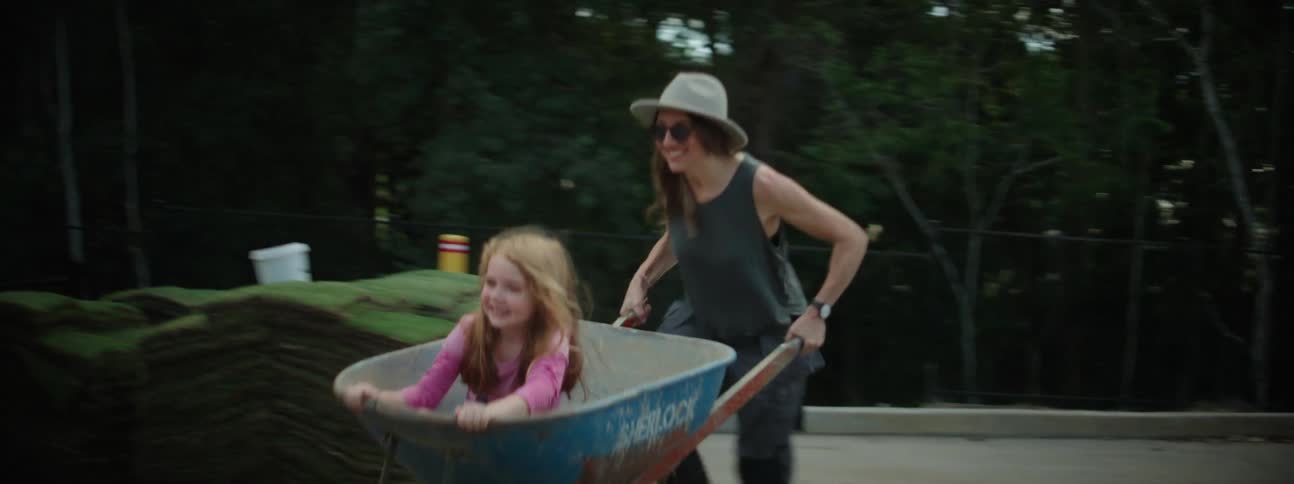 Mother and daughter playing on a wheelbarrow in the backyard