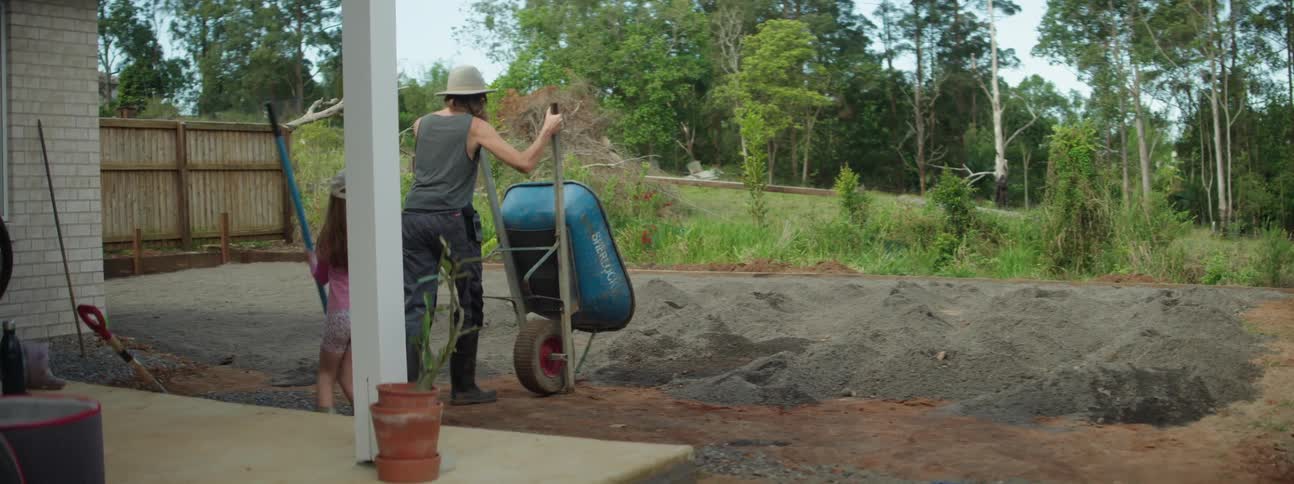 A mother and daughter using a wheel barrow in a garden