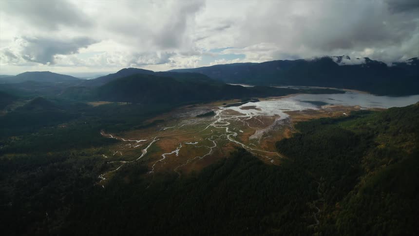 Aerial view of river estuaries flowing out of valley between wooded mountain ranges