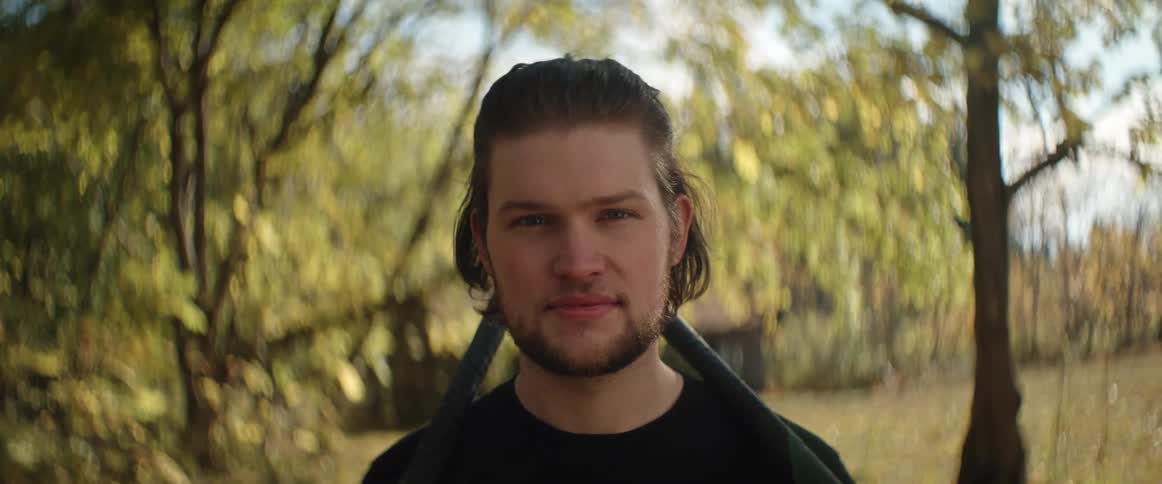 A man in a yellow autumn forest poses for a portrait