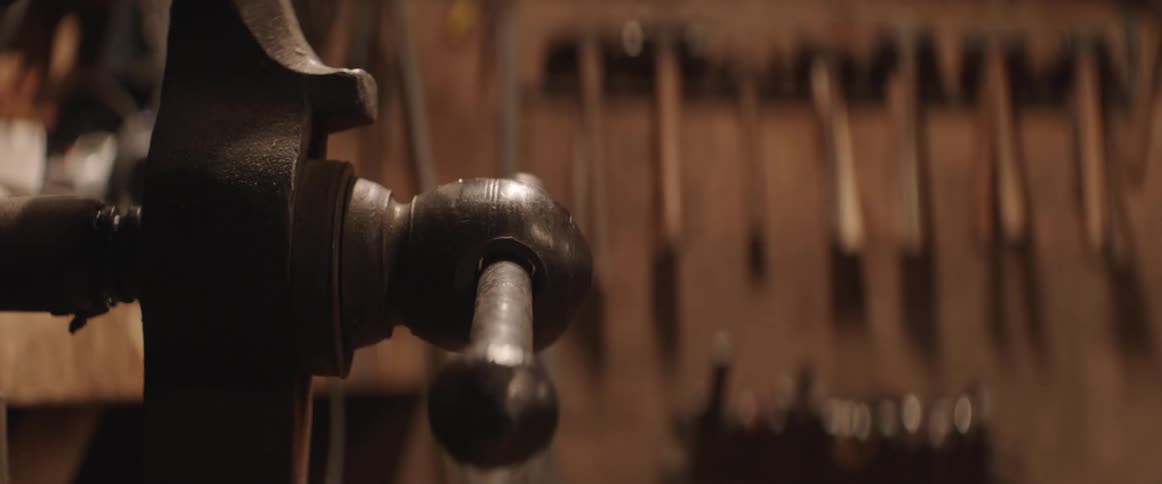 Close up of an iron vice attached to a workbench inside a carpenter workshop